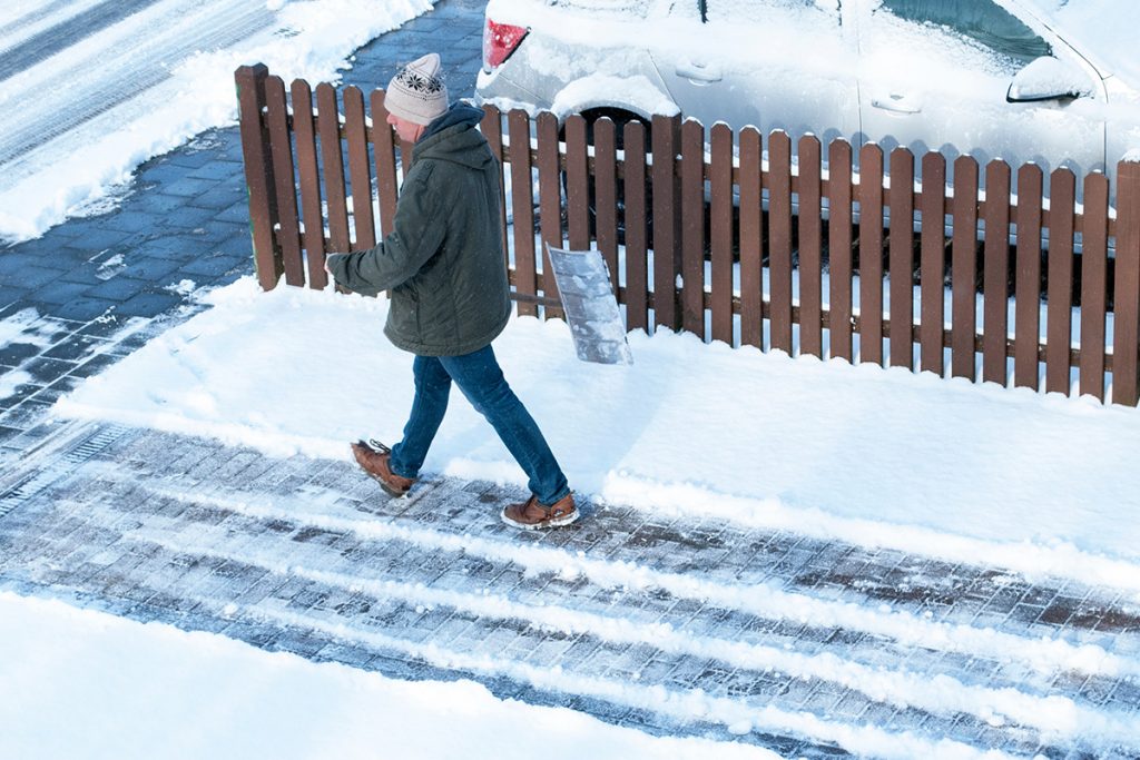 Grundstückseigentümer räumt Gehweg vor Wohnhaus – Beispiel für Räumpflicht auf Gehweg und Winterdienst Mieter Pflicht laut Hausordnung Winterdienstplan.